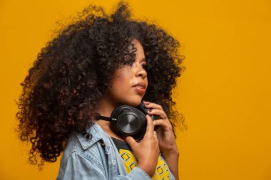 İnsanlar, müzik, duygu konsepti. Afro saç stili ile zevkli bir kadın melodi ile dans ediyor, gözlerini kapatıyor kulaklıkla yüksek sesle şarkı dinliyor. Kulaklıklı, güzel afro bir kadın.