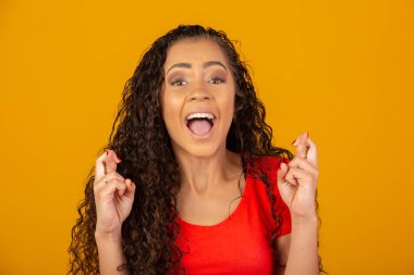 Kazanmak zorundayım. Neşeli genç esmer kadın dişlerini sıkar, parmaklarını çapraz yapar, arzulanan dilekleri yapar, kıvırcık saçlar, melez ırk, Afrikalı, Brezilyalı kız, iyi haberleri bekler, sarı duvarın üzerinde durur.