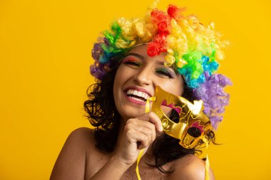 Karnaval gecesi için giyinmiş güzel bir kadın. Renkli bir peruk ve maskeyle karnavalın tadını çıkarmaya hazır gülümseyen kadın.