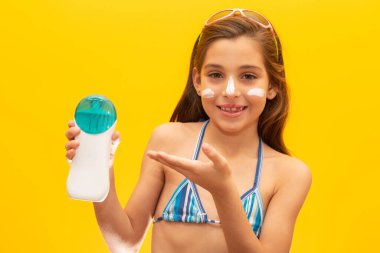 Mayo giymiş tatlı bir kız sunar güneş kremi