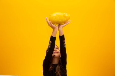 Sarı arka planda domuzcuk tutan kız