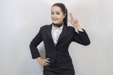 Beyaz arka planda yalnız poz veren şık kostümlü sevimli hostes.