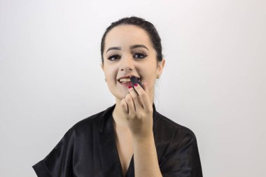 Esmer kadın beyaz arka planda makyaj yapıyor.