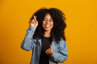 Kazanmak zorundayım. Neşeli genç esmer kadın dişlerini sıkar, parmaklarını çapraz yapar, arzulanan dilekleri yapar, kıvırcık saçlar, melez ırk, Afrikalı, Brezilyalı kız, iyi haberleri bekler, sarı duvarın üzerinde durur.