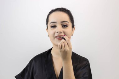 Esmer kadın beyaz arka planda makyaj yapıyor.