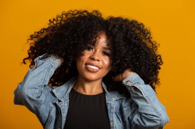 Kıvırcık saçlı, kameraya bakıp gülümseyen genç Afro-Amerikalı kadın. Kıvırcık saçlı, kameraya bakıp gülümseyen tatlı afro kız..
