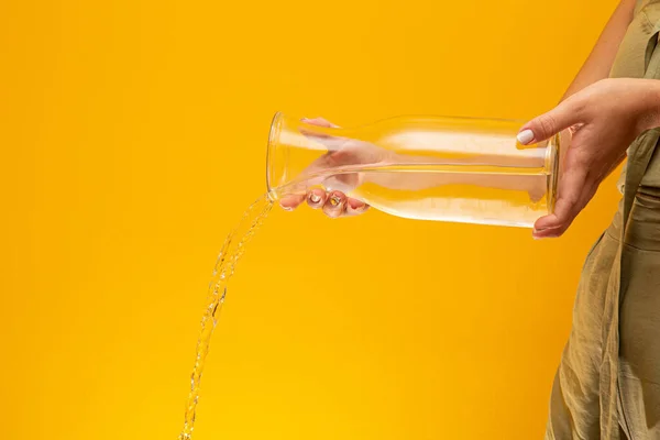 Water Pour into Glass. Water pouring. Splashing water on yellow background.