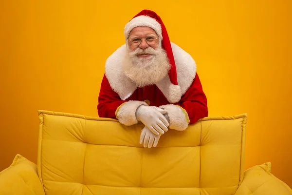 Papai Noel Sentado Sofá Amarelo Fundo Amarelo Com Espaço Cópia — Fotografia de Stock