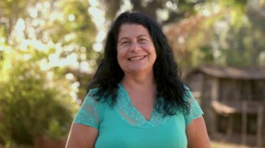 Bahçede poz veren gülümseyen olgun kadın.