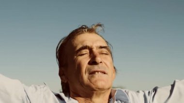 Olgun adam elini havaya kaldırıyor güneşli havanın tadını çıkarıyor
