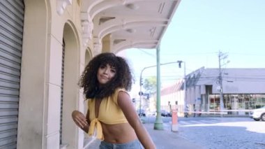 Şehrin arka planında dans eden şık kıvırcık kadın