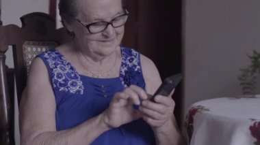 Gözlüklü yaşlı kadının akıllı telefon kullanmasını yakından izle