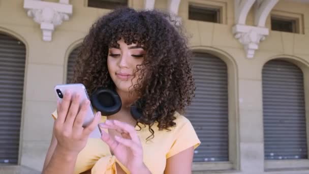 Stylisch Gelockte Frau Posiert Mit Smartphone Vor Stadtkulisse — Stockvideo