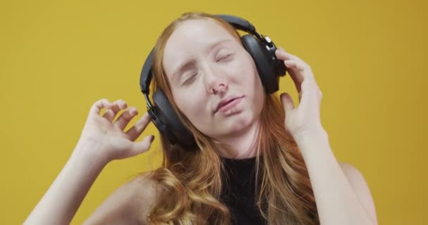 Sarı Arka Planda Kol Hareketi Yapan Kızıl Saçlı Genç Kadın — Stok video