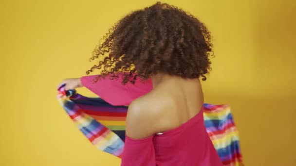 若いブラジルの巻き女性ジェスチャーや黄色の背景に虹のLgbtの旗でポーズ — ストック動画