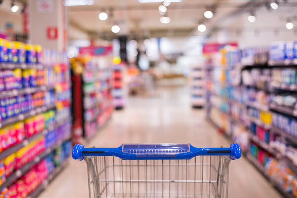 Shopping cart view in Supermarket aisle with product shelves abstract blur defocused background