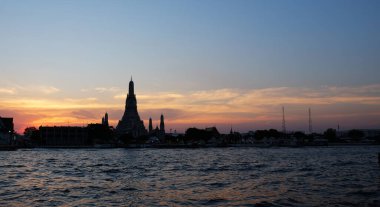 Thai tapınağı Wat Arun gün batımında Chao Phraya nehrinin kıyısında duruyor. Akşam manzarası.