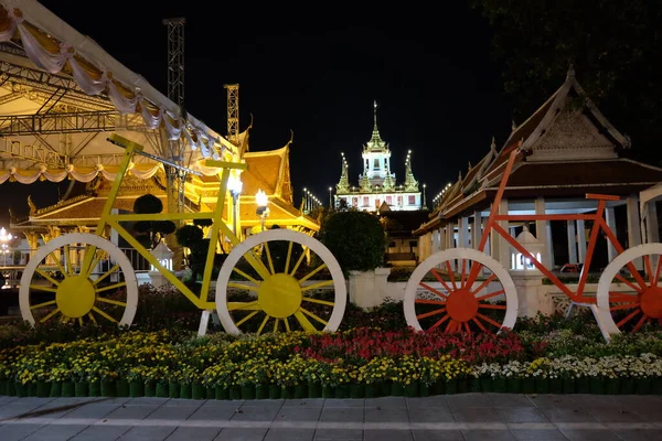 Decorative bicycles stand near the flowerbed at night.