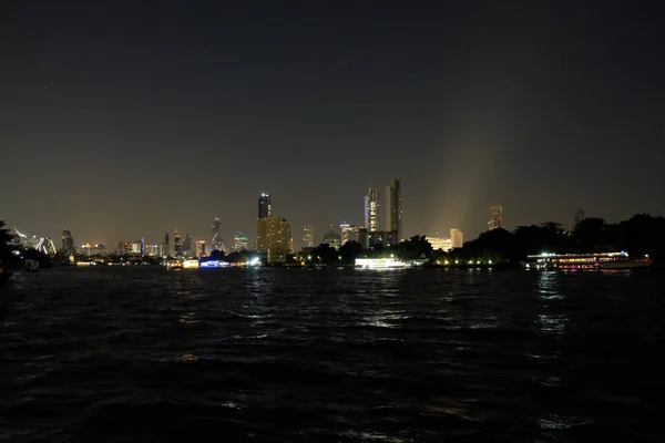 Skyscrapers stand on the banks of the river. Night urban landscape. Lights of the night city.