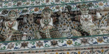 Several Hindu sculptures support the walls of the temple. The walls of the building are decorated with floral patterns.