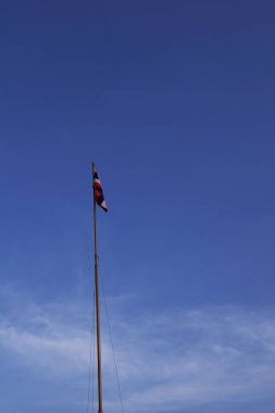 Tayland bayrağı mavi gökyüzüne karşı bayrak direğinde dalgalanıyor..