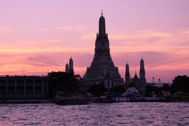 Thai tapınağı Wat Arun gün batımında Chao Phraya nehrinin kıyısında duruyor. Akşam manzarası.