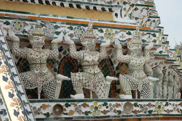 Several Hindu sculptures support the walls of the temple. The walls of the building are decorated with floral patterns.