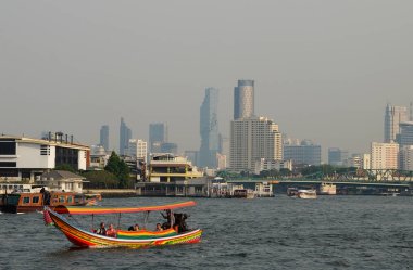 Bangkok, Tayland, 26 Aralık 2018. İnsanlar Chao Phraya nehri boyunca çok renkli küçük bir tekneyle modern gökdelenlerin arka planına doğru yol alıyorlar..