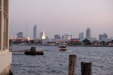 Bangkok, Tayland, 25 Aralık 2018. Nehir rıhtımından şehrin gökdelenlerinin manzarası. Chao Phraya Nehri 'nde küçük tekneler yelken açıyor..