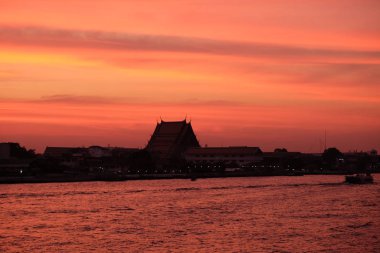 Bangkok 'taki Chao Phraya Nehri üzerinde inanılmaz bir gün batımı. Nehir kenarındaki binaların siluetleri.