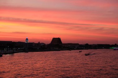 Bangkok 'taki Chao Phraya Nehri üzerinde inanılmaz bir gün batımı. Nehir kenarındaki binaların siluetleri.