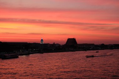 Bangkok 'taki Chao Phraya Nehri üzerinde inanılmaz bir gün batımı. Nehir kenarındaki binaların siluetleri.