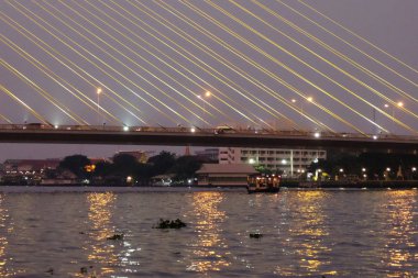 Gece Bangkok 'ta bir nehrin üzerindeki büyük bir asma köprünün kabloları..