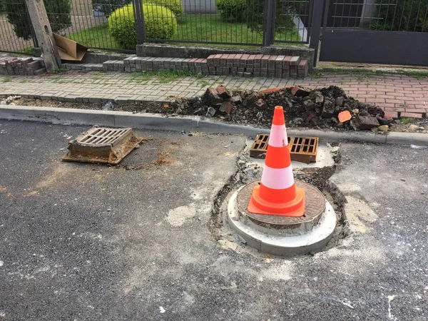 A bright cone to indicate road work is on the pavement.