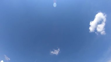 Kümülüs bulutları güneşli bir günde mavi gökyüzünde hareket eder. Uçak havada uçuyor. Zaman Uygulaması.
