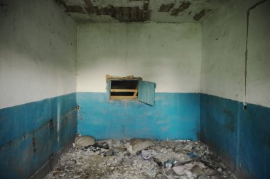 Terk edilmiş bir binanın ortaya çıkışı. Eski püskü duvarlar. Yırtık kablolar ve yerdeki çöpler..