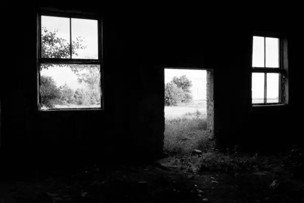 一座废弃建筑的墙上有两扇破碎的窗户和一个空的门口 — 图库照片
