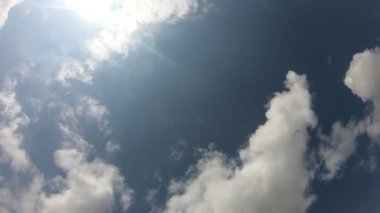 Kümülüs bulutları mavi gökyüzünde hareket eder. Güneş ışınları. Zaman Uygulaması
