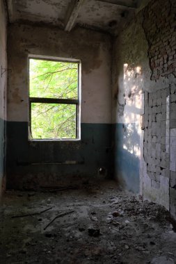 Pencere ışığı terk edilmiş bir odayı aydınlatıyor. Terk edilmiş tuğla bina.