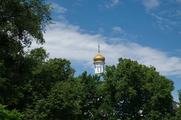 The dome of the Orthodox church over the trees. Golden dome against the blue sky.