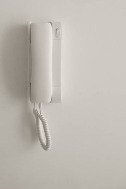 Beyaz bir duvarda beyaz bir telefon. Kopyalama alanı.
