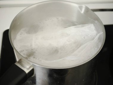 Gevrek dolu poşetler tavada kaynıyor. Yemek pişirmek. Kaynar su.