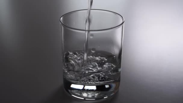 純粋な輝く水は灰色のテーブルの上にガラスを注ぐ ダイエットと減量のためのエコ製品を食べる — ストック動画