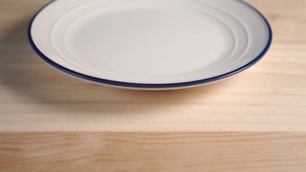 Close White Plate Blue Stripe Edge Wooden Background Camera Track — ストック動画