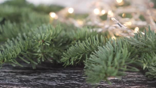 가문비나무 가지에 아름다운 바늘이 반짝이는 크리스마스 갈랜드의 배경에 노란색 불빛이 — 비디오