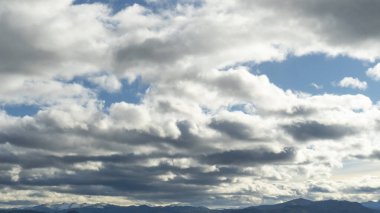 Dağların zirvelerinin üstündeki parlak mavi gökyüzünde renkli akşam bulutları. Güzel manzara arkaplanı