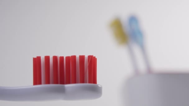 Hand Squeezes Blue Toothpaste White Plastic Toothbrush Red Bristles Glass — Stock Video