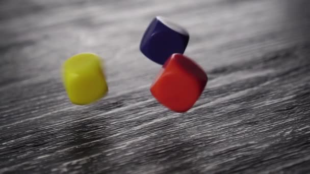 Три Разноцветных Игровых Кости Падают Черный Текстурированный Старый Деревянный Стол — стоковое видео