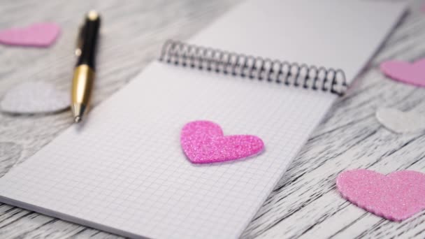 Λαμπερές Ροζ Και Άσπρες Χάρτινες Καρδιές Πέφτουν Ένα Ανοιχτό Σημειωματάριο — Αρχείο Βίντεο