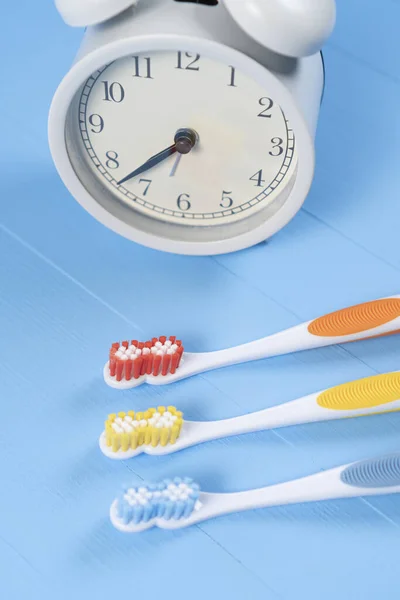 Classic Alarm Clock Three Bright Plastic Toothbrushes Orange Yellow Blue — Stock Photo, Image